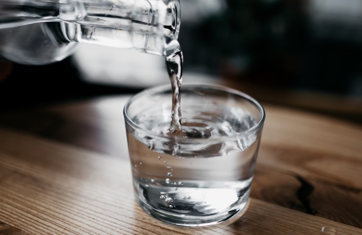 Bottiglia d'acqua versata in un bicchiere